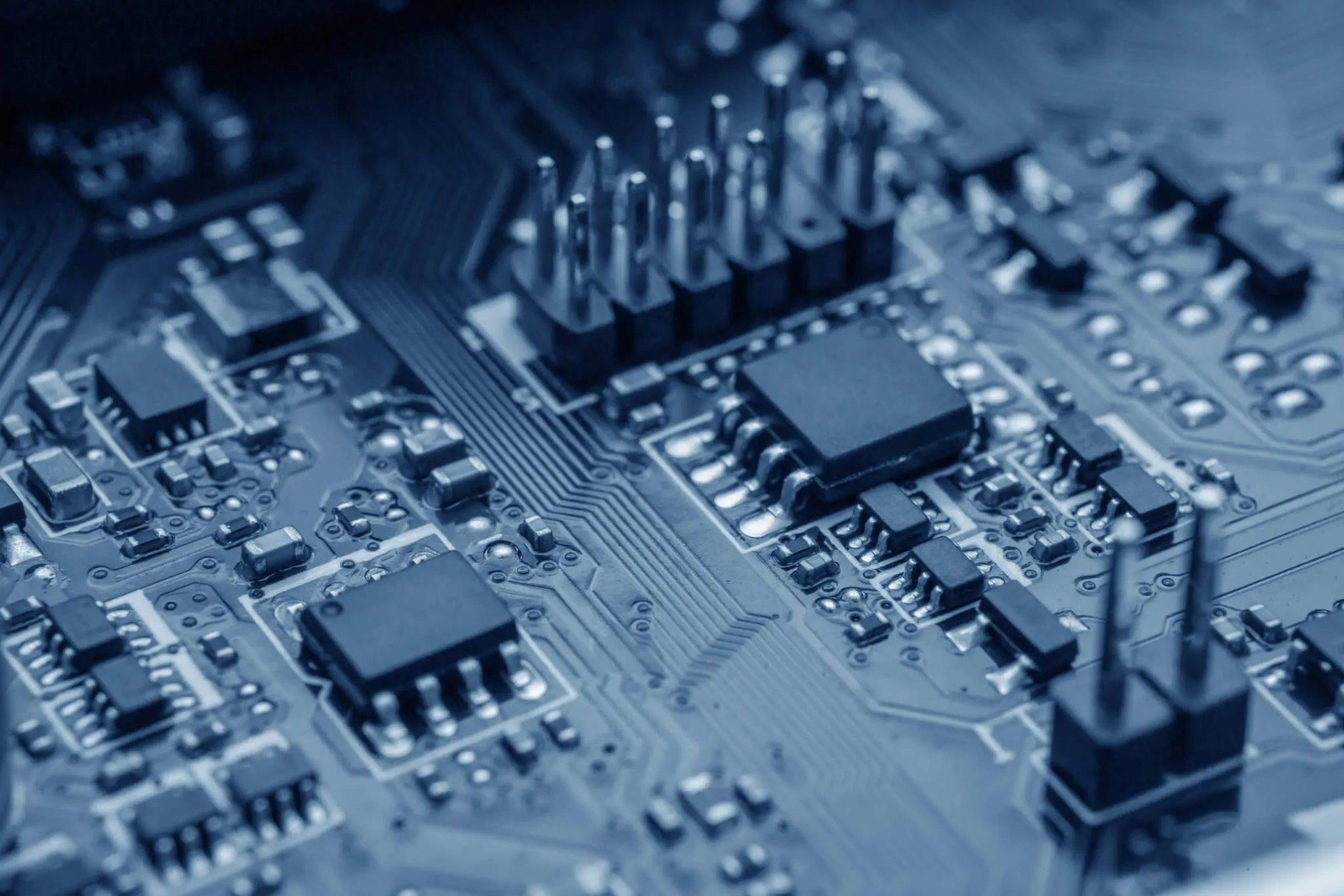 Close-up of microchips and electronic components mounted on a blue printed circuit board with visible connections and pins.