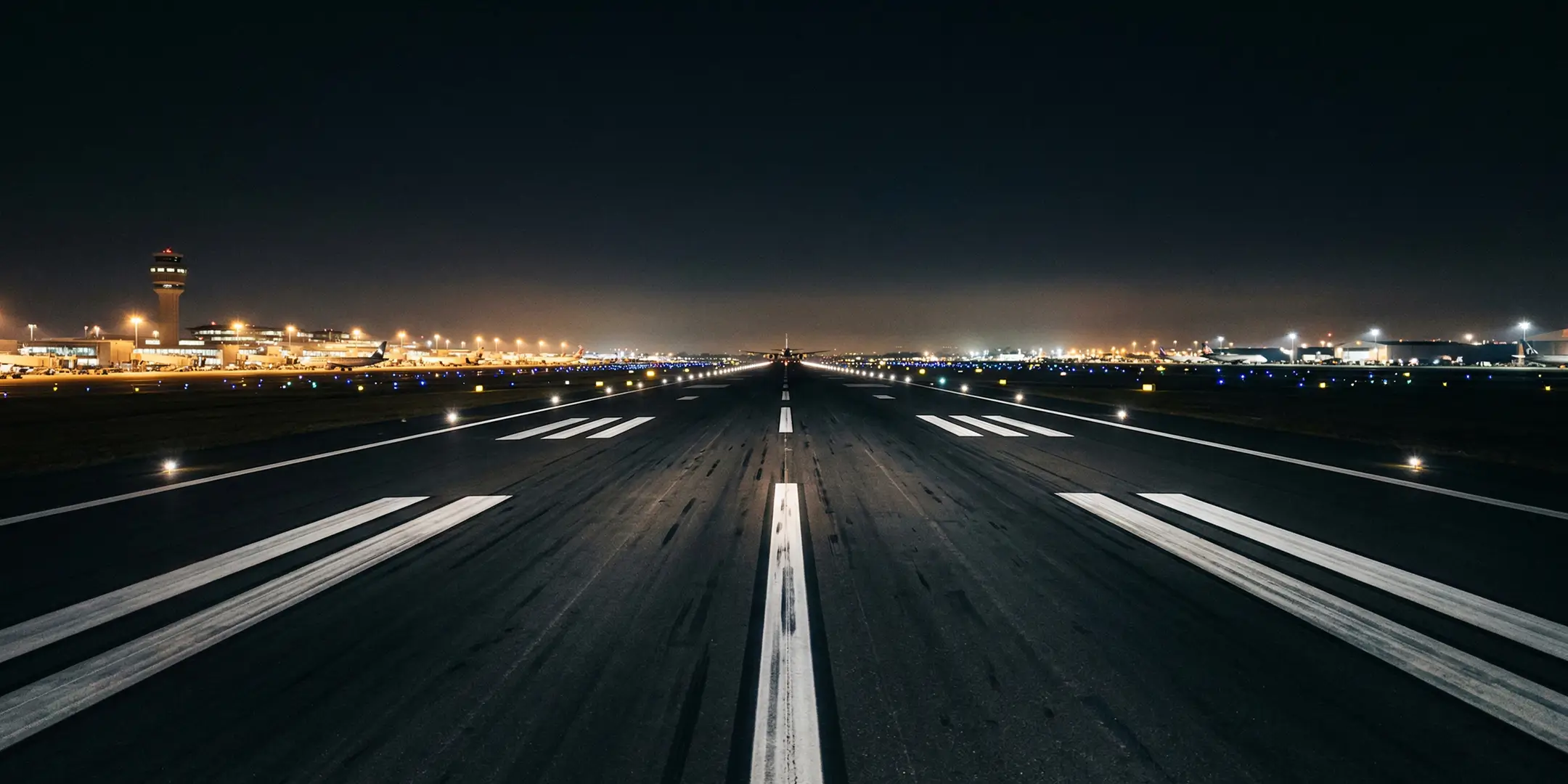Blick auf eine Flughafenlandebahn, die von Flugzeugscheinwerfern beleuchtet wird