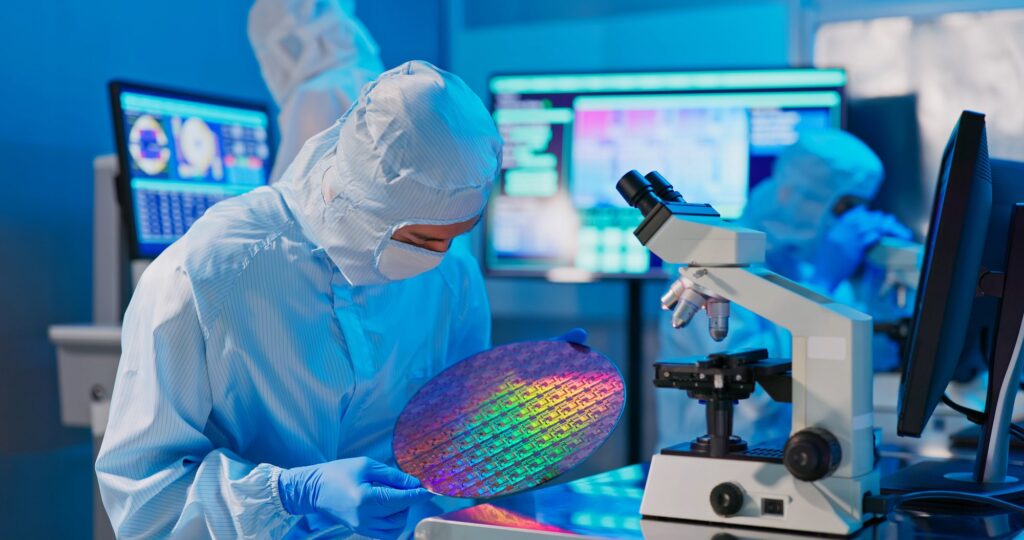 Un technicien dans une salle blanche inspecte une plaquette de silicium